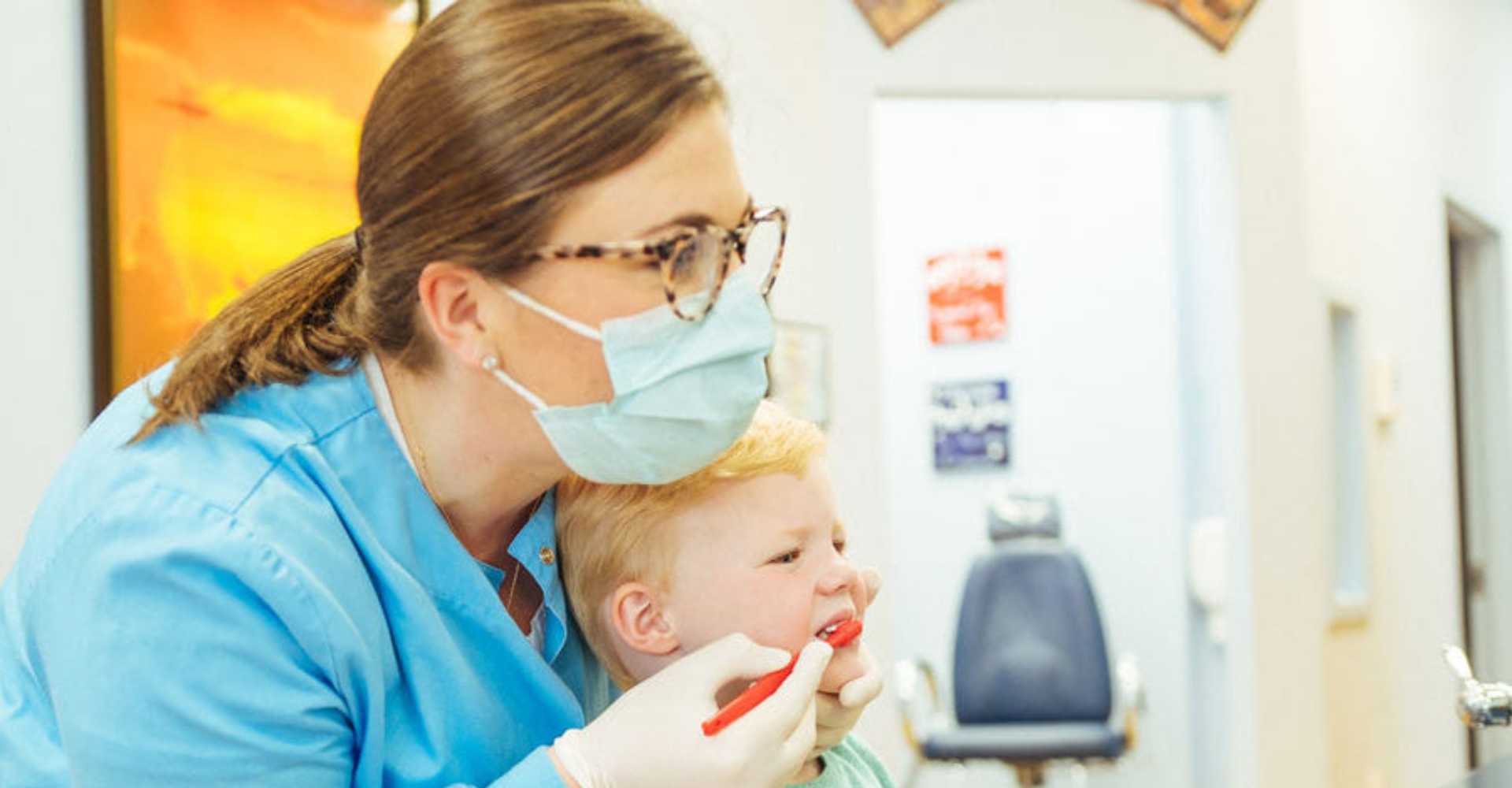 Dentist teaching a kid to bruch his teeth